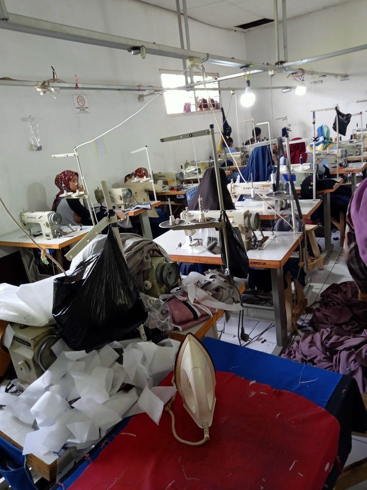 Rows of sewing machines with operators at work and an iron ready for finishing